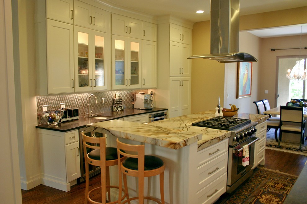 Inspiration för klassiska kök, med en rustik diskho, luckor med infälld panel, vita skåp, granitbänkskiva, stänkskydd med metallisk yta, stänkskydd i metallkakel, mellanmörkt trägolv, en köksö och integrerade vitvaror