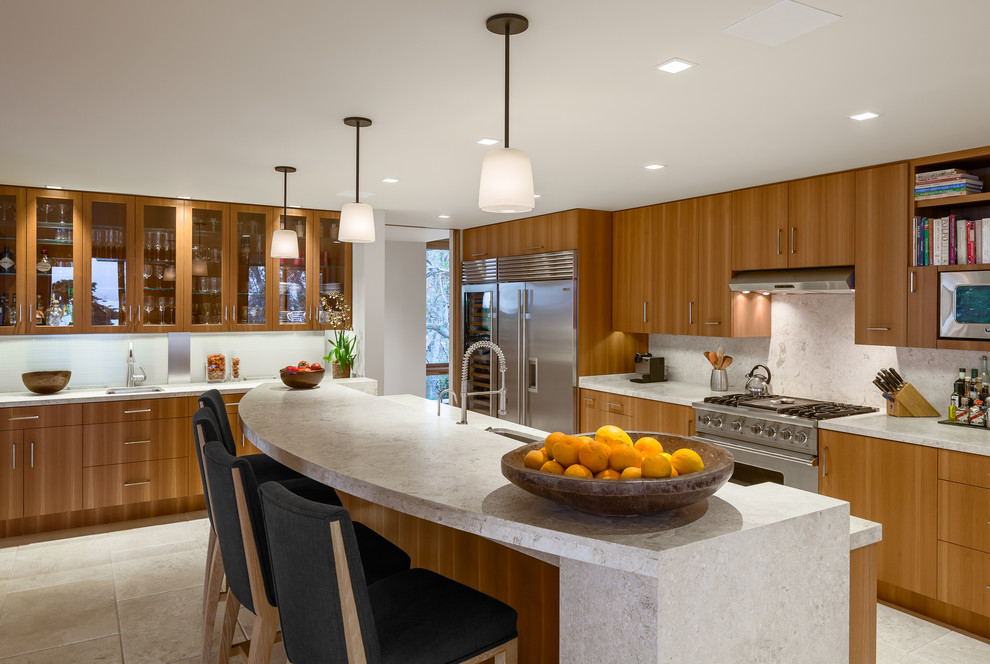 This is an example of a contemporary kitchen in Santa Barbara with flat-panel cabinets, medium wood cabinets, white splashback, stainless steel appliances and an island.