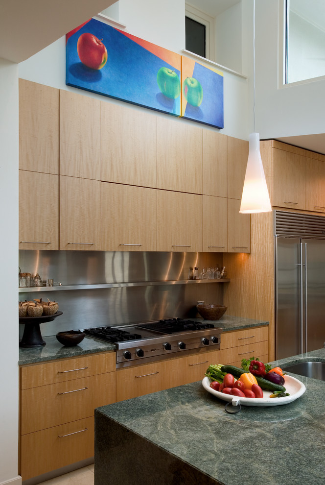 Modelo de cocina comedor contemporánea con fregadero integrado, armarios con paneles lisos, puertas de armario de madera clara, encimera de esteatita y electrodomésticos de acero inoxidable