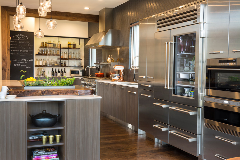 This is an example of a large contemporary kitchen/diner in Dallas with flat-panel cabinets, stainless steel appliances, dark hardwood flooring, an island, stainless steel cabinets, engineered stone countertops, black splashback, mosaic tiled splashback, brown floors and white worktops.