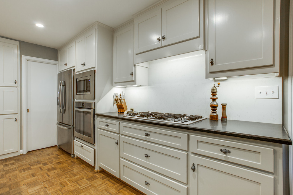 Elegant medium tone wood floor kitchen photo in Dallas with an undermount sink, shaker cabinets, white cabinets, white backsplash, stainless steel appliances and an island