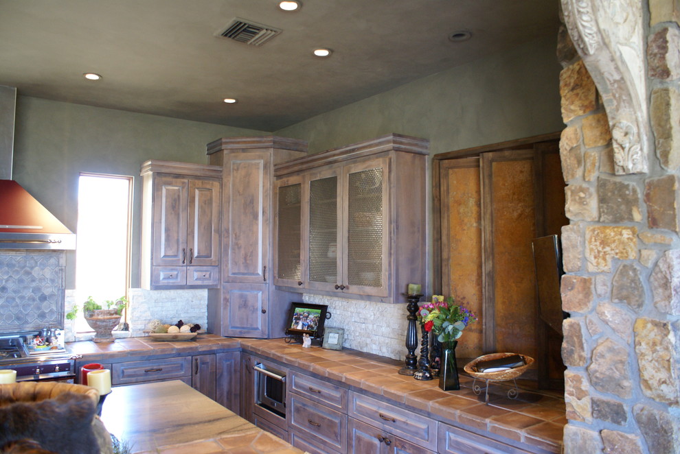 Idéer för att renovera ett rustikt kök, med en rustik diskho, luckor med upphöjd panel, bruna skåp, kaklad bänkskiva, beige stänkskydd, stänkskydd i stenkakel, mörkt trägolv och en köksö