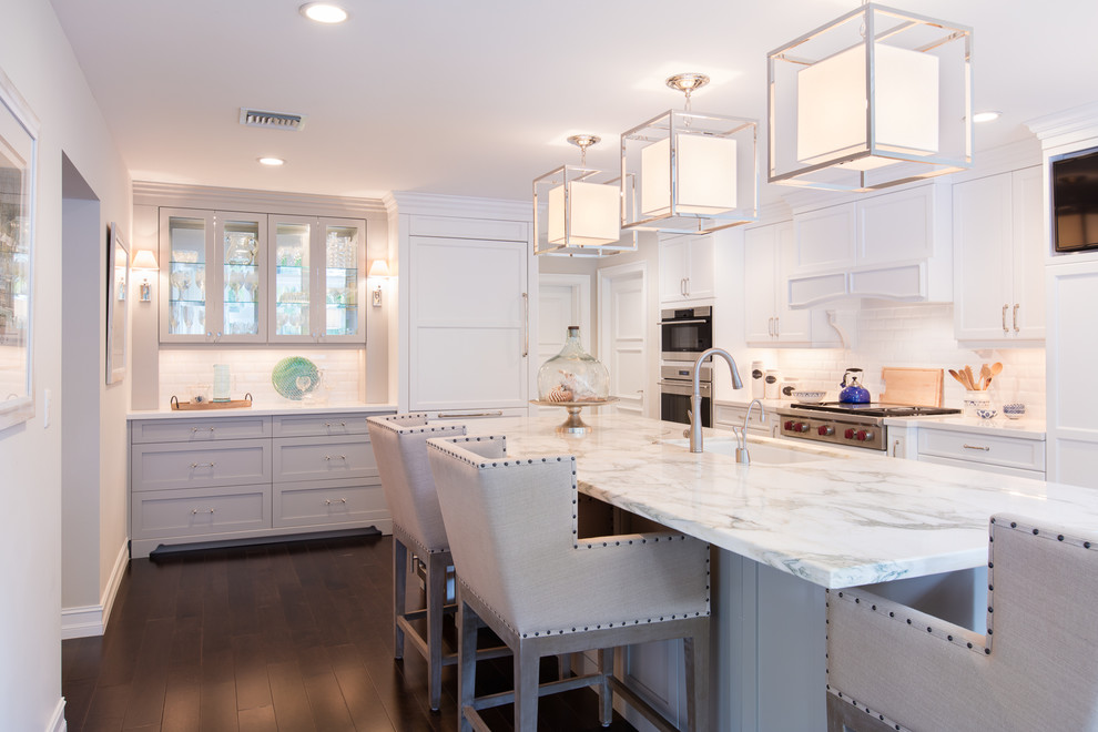 Eat-in kitchen - large coastal galley dark wood floor and brown floor eat-in kitchen idea in Other with an undermount sink, shaker cabinets, white cabinets, marble countertops, white backsplash, subway tile backsplash, paneled appliances, an island and gray countertops