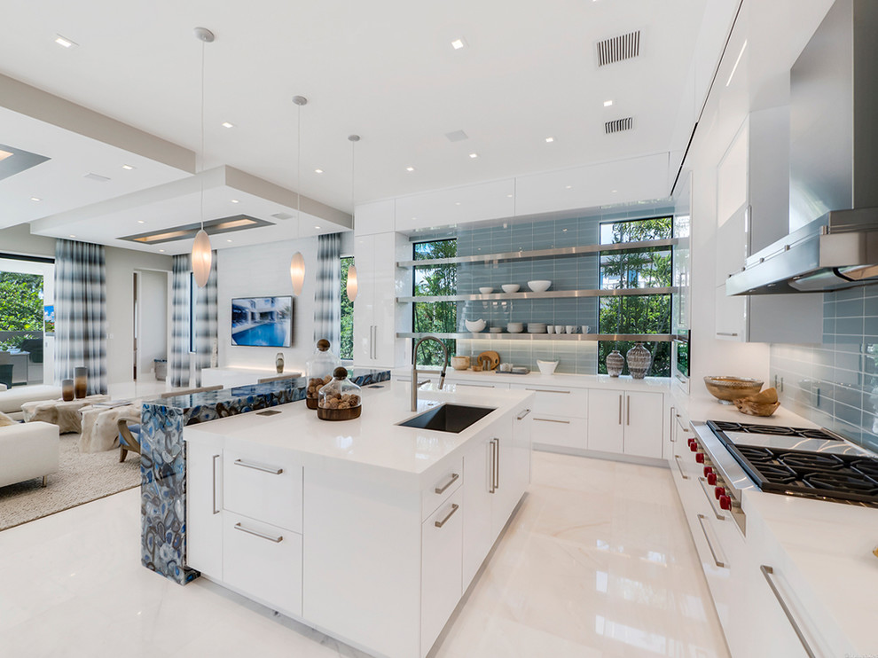 This is an example of a large contemporary l-shaped open plan kitchen in Miami with flat-panel cabinets, an island, a submerged sink, white cabinets, blue splashback, glass tiled splashback and marble flooring.