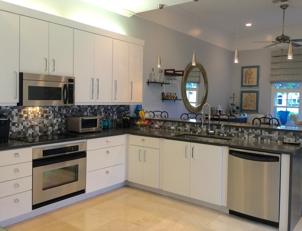 This is an example of a medium sized modern l-shaped kitchen in Miami with a submerged sink, flat-panel cabinets, white cabinets, engineered stone countertops, metallic splashback, mosaic tiled splashback, stainless steel appliances, travertine flooring and no island.