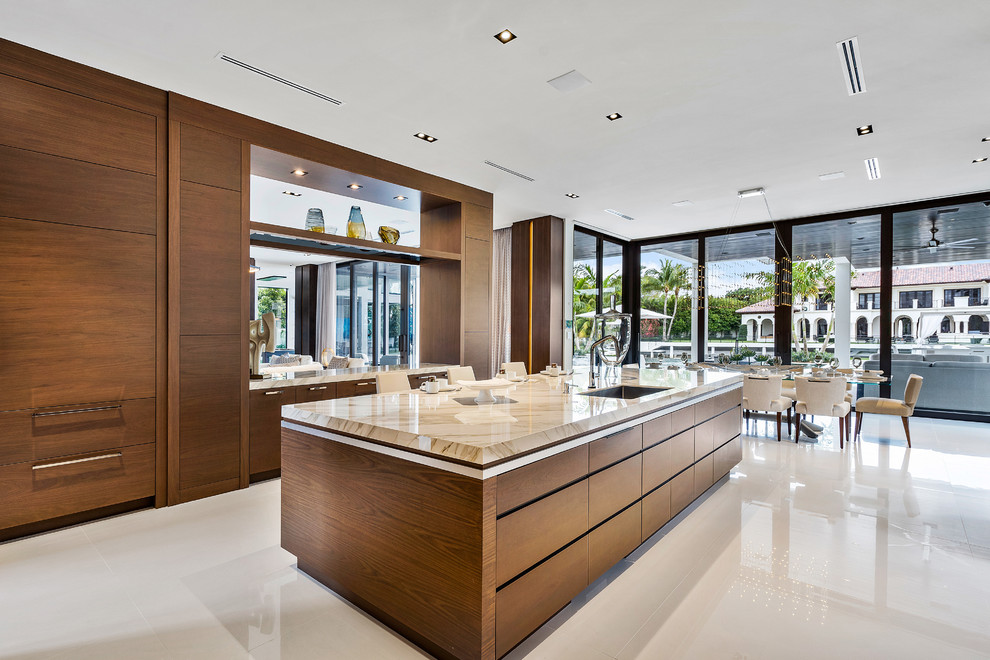 Large modern kitchen in Miami with a built-in sink, flat-panel cabinets, medium wood cabinets, onyx worktops, beige splashback, marble flooring, an island, white floors and beige worktops.