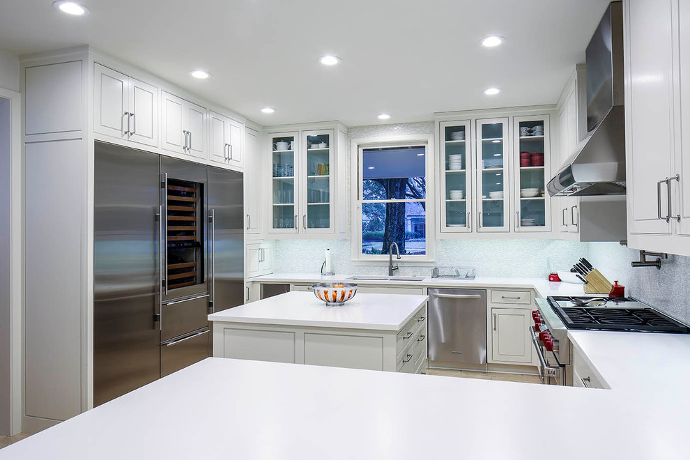 Eat-in kitchen - mid-sized contemporary u-shaped limestone floor eat-in kitchen idea in New Orleans with an undermount sink, flat-panel cabinets, white cabinets, solid surface countertops, multicolored backsplash, glass tile backsplash, stainless steel appliances and an island