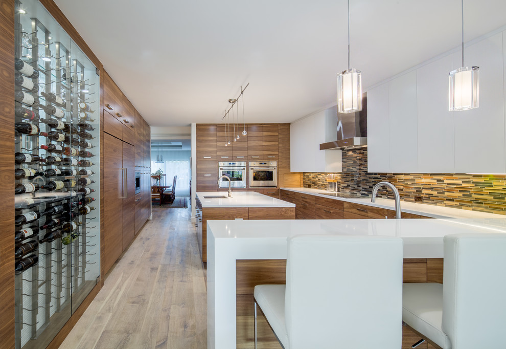 Expansive contemporary u-shaped kitchen in Miami with a submerged sink, flat-panel cabinets, medium wood cabinets, engineered stone countertops, multi-coloured splashback, glass sheet splashback, integrated appliances, light hardwood flooring and an island.