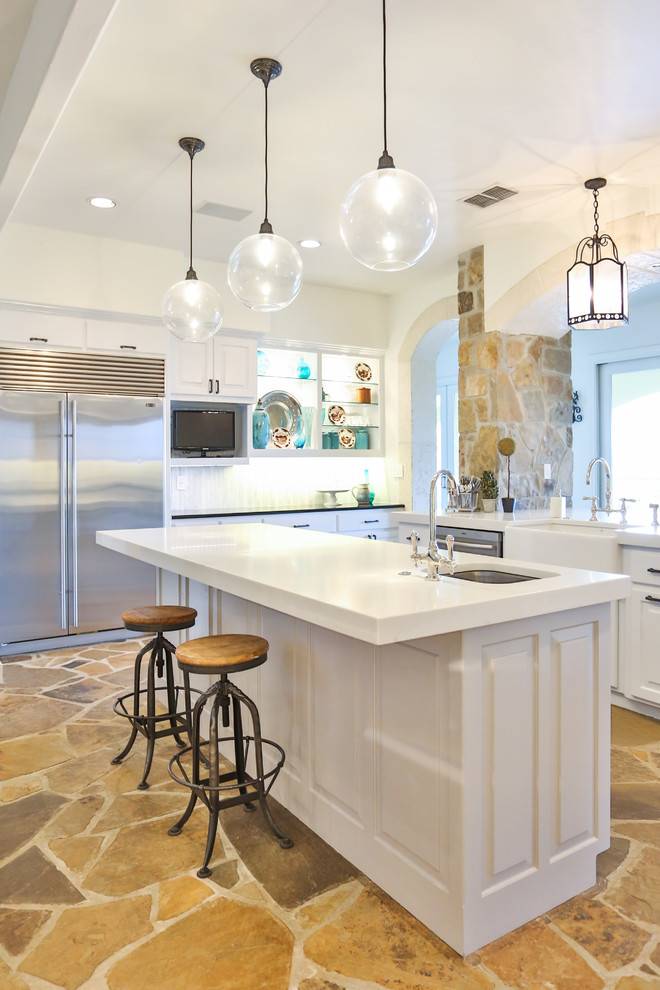 Large elegant u-shaped limestone floor and brown floor eat-in kitchen photo in Austin with a farmhouse sink, raised-panel cabinets, white cabinets, glass countertops, white backsplash, marble backsplash, stainless steel appliances, an island and yellow countertops