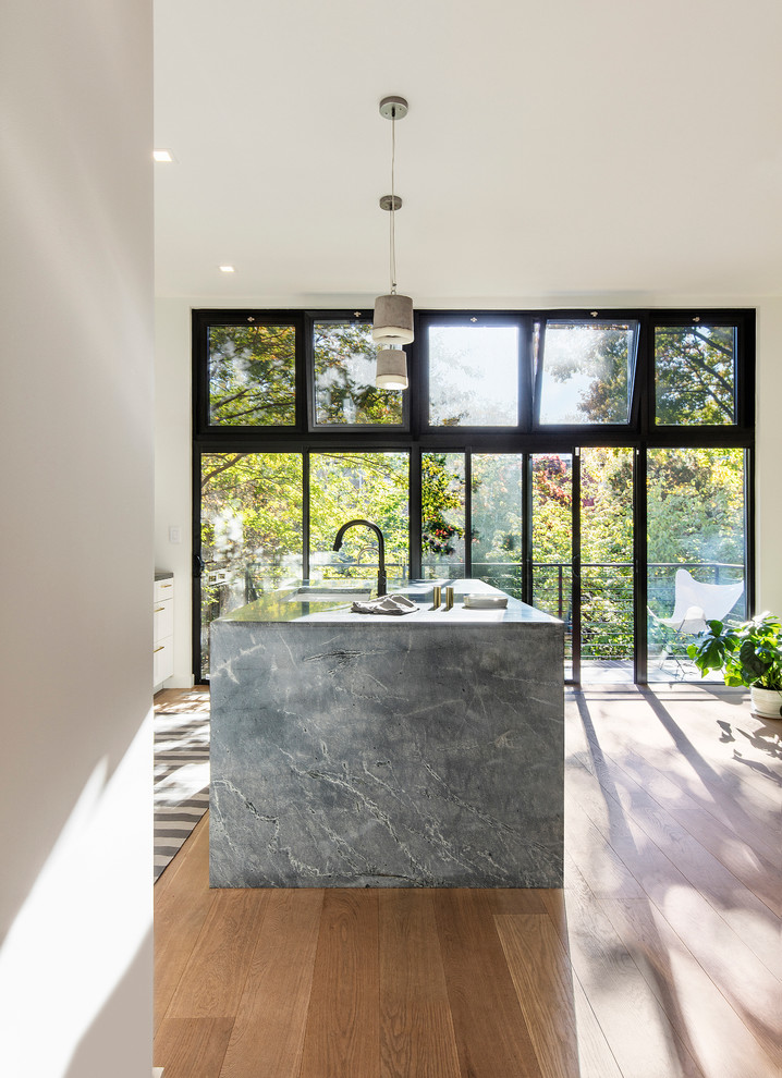 This is an example of a medium sized contemporary kitchen/diner in New York with a submerged sink, flat-panel cabinets, yellow cabinets, marble worktops, light hardwood flooring and an island.