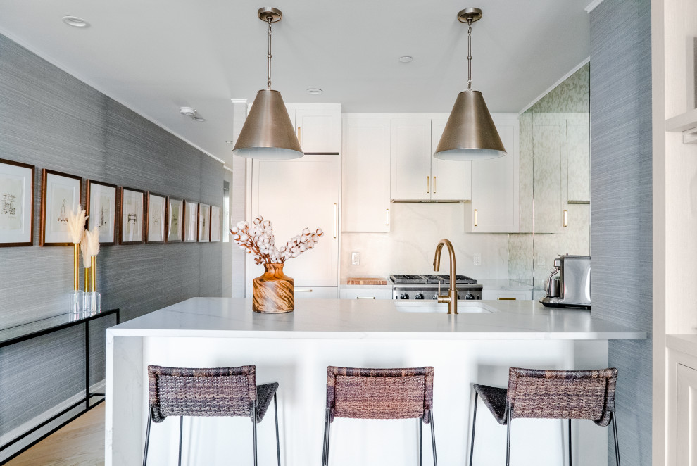 Inspiration for a contemporary galley light wood floor and beige floor kitchen remodel in New York with an undermount sink, shaker cabinets, white cabinets, white backsplash, paneled appliances, a peninsula and white countertops