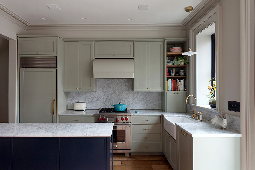 Klassische Küche mit grünen Schränken, Marmor-Arbeitsplatte, Rückwand aus Marmor, braunem Holzboden und Halbinsel in New York