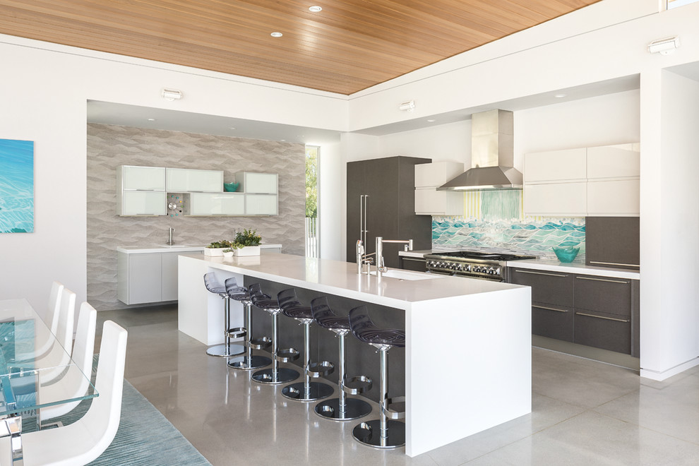 Photo of a midcentury l-shaped kitchen/diner in Other with a submerged sink, flat-panel cabinets, grey cabinets, blue splashback, integrated appliances, an island, concrete flooring and grey floors.