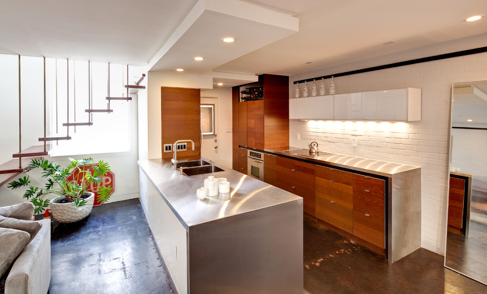 Ejemplo de cocina moderna con encimera de acero inoxidable, fregadero integrado, armarios con paneles lisos y puertas de armario de madera en tonos medios