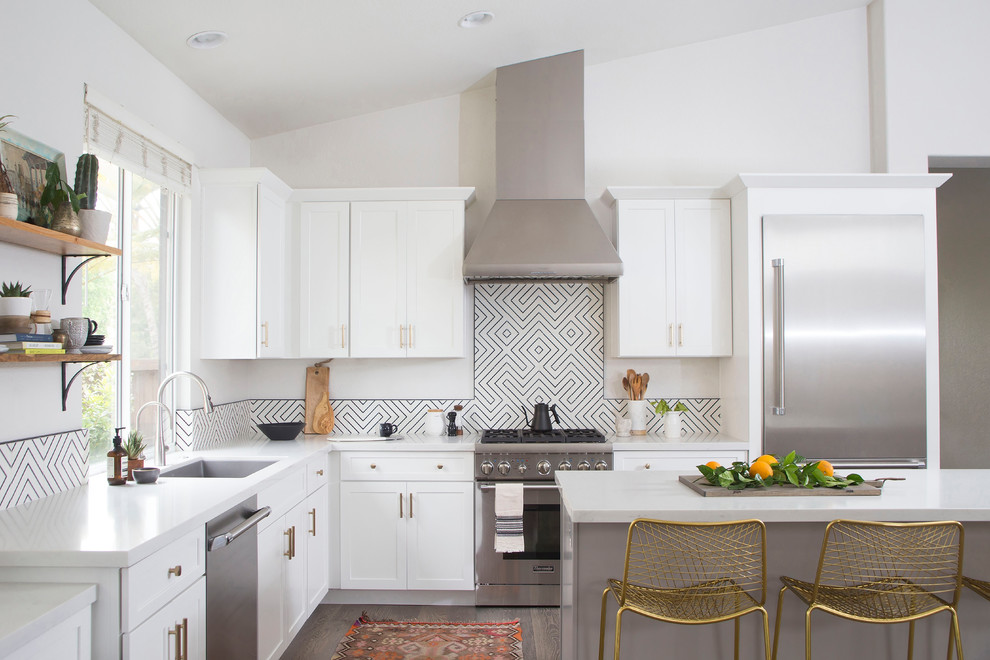 Inspiration for a mid-sized transitional l-shaped brown floor and dark wood floor open concept kitchen remodel in Denver with shaker cabinets, white cabinets, white backsplash, stainless steel appliances, an island, quartz countertops, cement tile backsplash and an undermount sink
