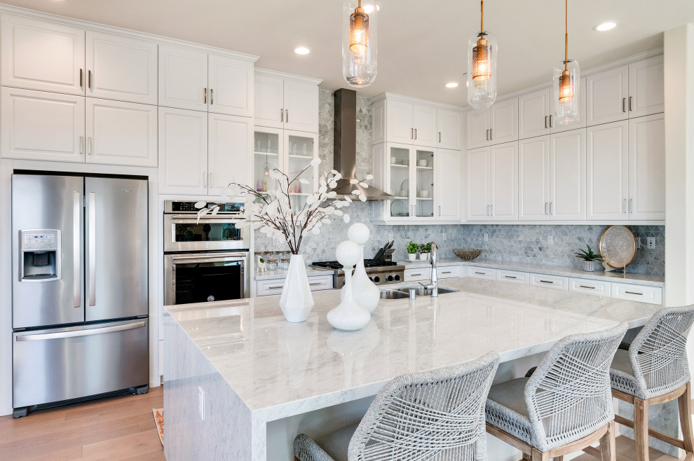 Medium sized traditional l-shaped kitchen in Los Angeles with a double-bowl sink, raised-panel cabinets, white cabinets, grey splashback, stainless steel appliances, medium hardwood flooring, an island, brown floors and grey worktops.
