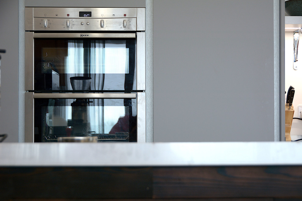 Esempio di una cucina design di medie dimensioni con ante lisce, ante grigie, top in acciaio inossidabile e pavimento in cemento