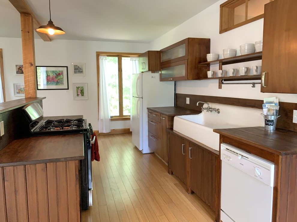 Foto på ett litet amerikanskt brun kök, med en rustik diskho, släta luckor, skåp i mellenmörkt trä, träbänkskiva, vita vitvaror, ljust trägolv, en köksö och beiget golv