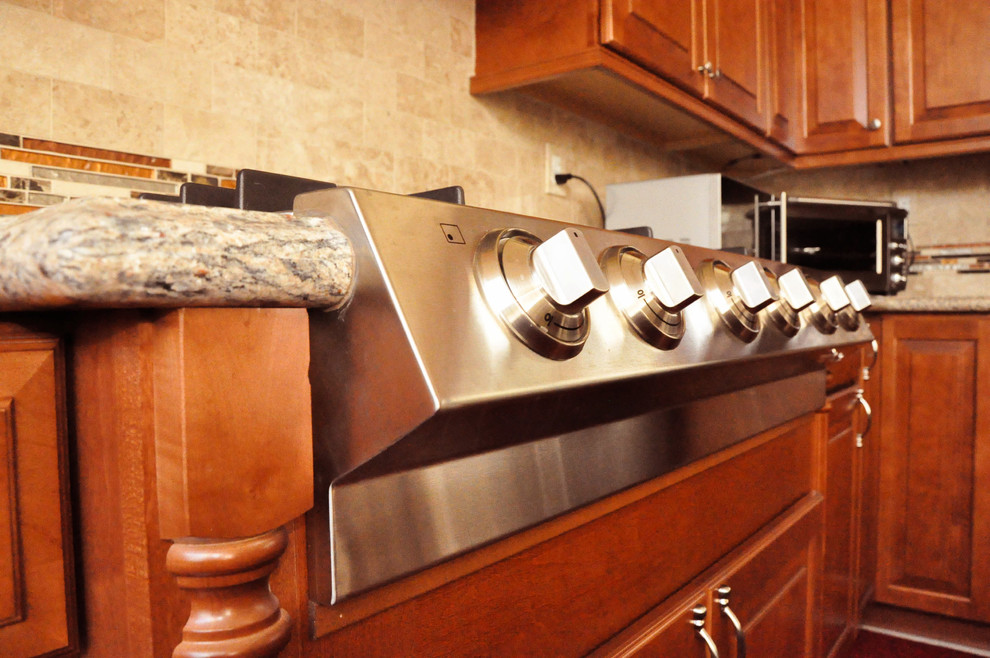 Klassisk inredning av ett mellanstort kök, med rostfria vitvaror, en integrerad diskho, luckor med upphöjd panel, skåp i mellenmörkt trä, granitbänkskiva, flerfärgad stänkskydd, stänkskydd i keramik och en köksö