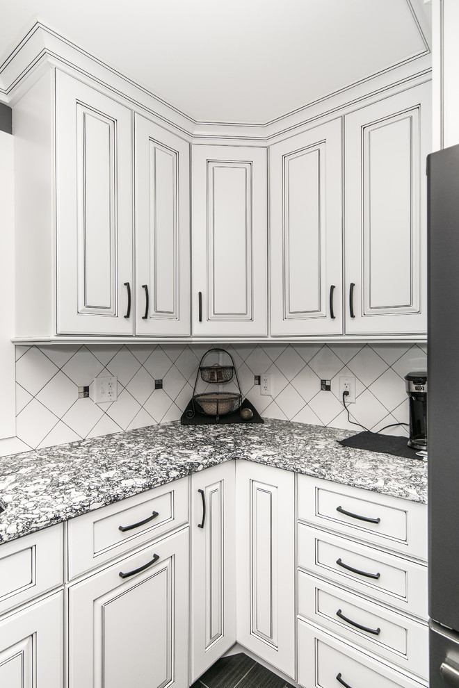 Large minimalist l-shaped porcelain tile and black floor eat-in kitchen photo in Bridgeport with an undermount sink, raised-panel cabinets, white cabinets, white backsplash, ceramic backsplash, black appliances, an island and multicolored countertops