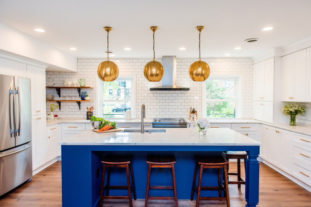Mid-sized transitional u-shaped medium tone wood floor kitchen photo in Other with shaker cabinets, quartz countertops, white backsplash, stainless steel appliances, an island, white countertops, an undermount sink, white cabinets and subway tile backsplash