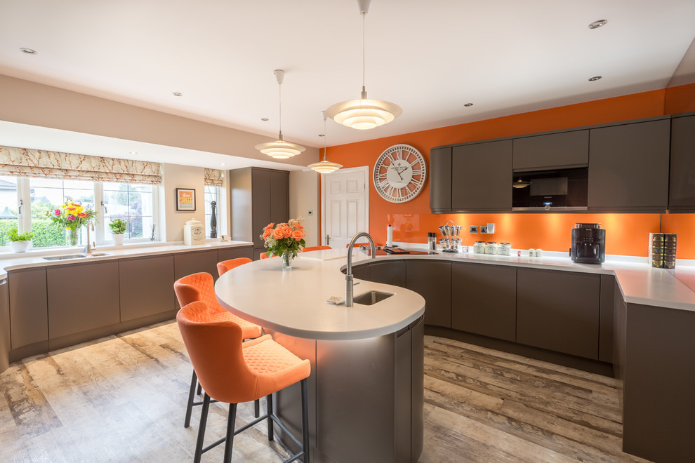 Moderne Küche in U-Form mit Unterbauwaschbecken, flächenbündigen Schrankfronten, braunen Schränken, Küchenrückwand in Orange, Glasrückwand, Halbinsel, braunem Boden und weißer Arbeitsplatte in Sonstige