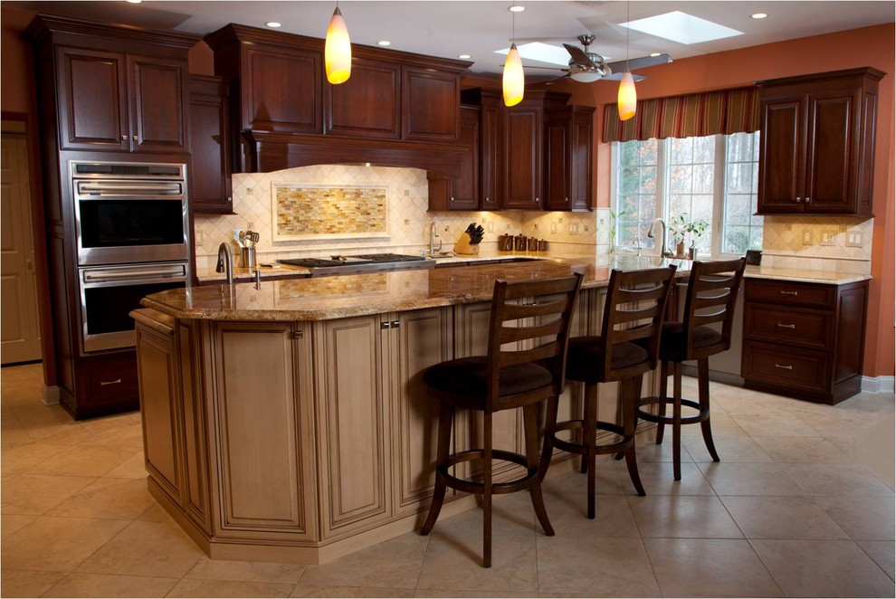 Large elegant l-shaped limestone floor open concept kitchen photo in Bridgeport with an undermount sink, raised-panel cabinets, dark wood cabinets, granite countertops, beige backsplash, stone tile backsplash, stainless steel appliances and an island