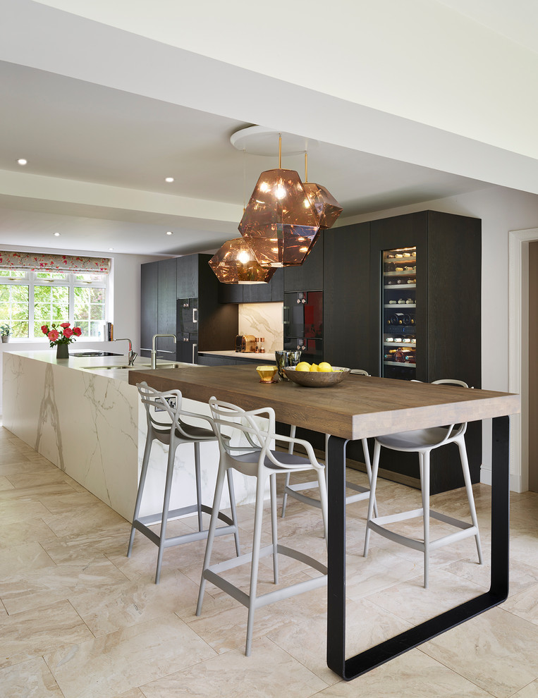 This is an example of a contemporary galley kitchen in Other with flat-panel cabinets, dark wood cabinets, black appliances, an island, beige floors and white worktops.