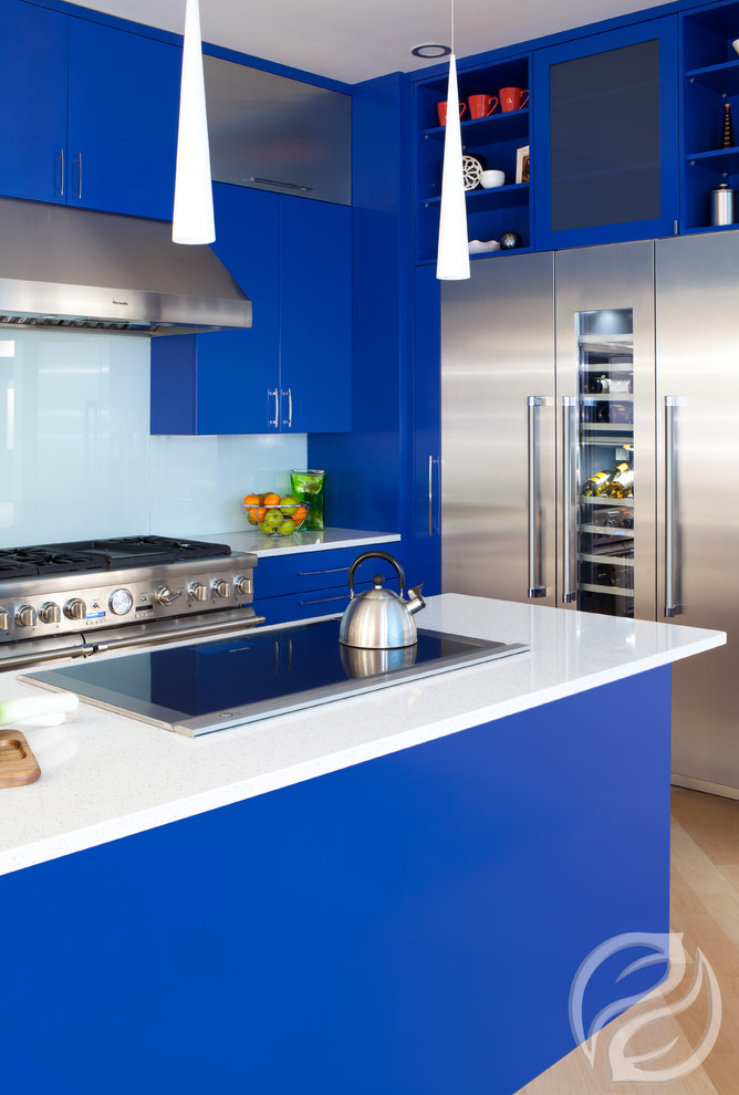Esempio di una cucina contemporanea chiusa e di medie dimensioni con ante lisce, ante blu, top in quarzo composito, paraspruzzi bianco, paraspruzzi con lastra di vetro, elettrodomestici in acciaio inossidabile e parquet chiaro