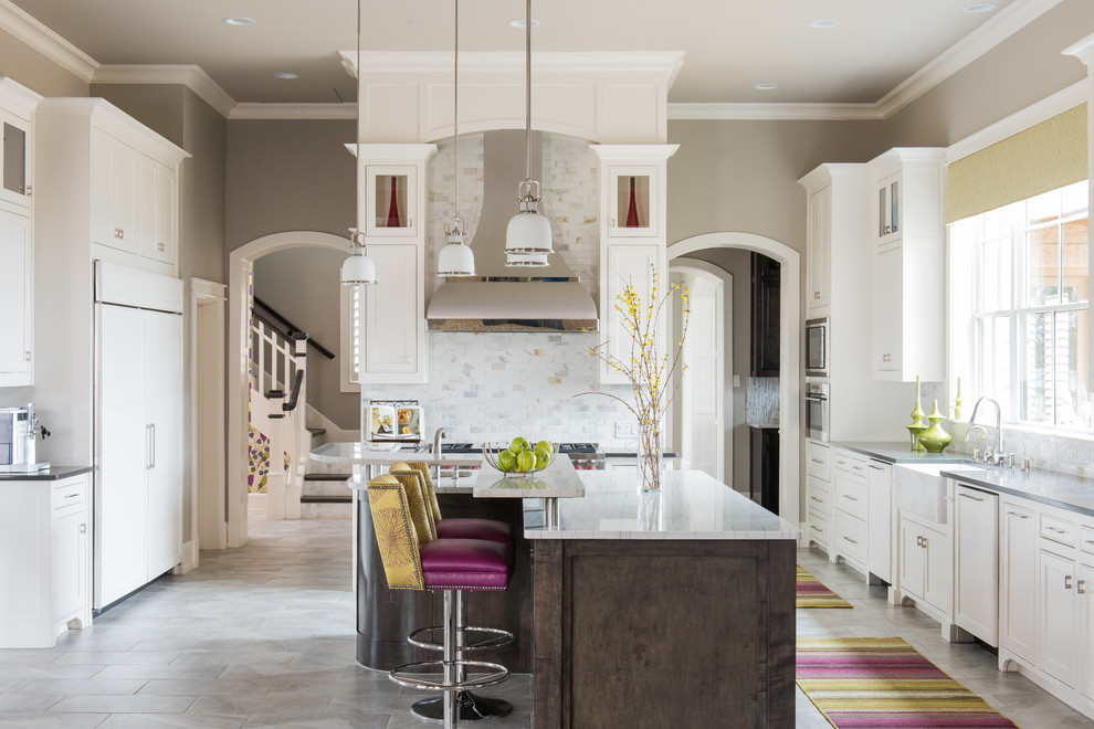 Inspiration for an expansive traditional u-shaped kitchen/diner in Dallas with a belfast sink, shaker cabinets, white cabinets, engineered stone countertops, white splashback, metro tiled splashback, stainless steel appliances, porcelain flooring and an island.