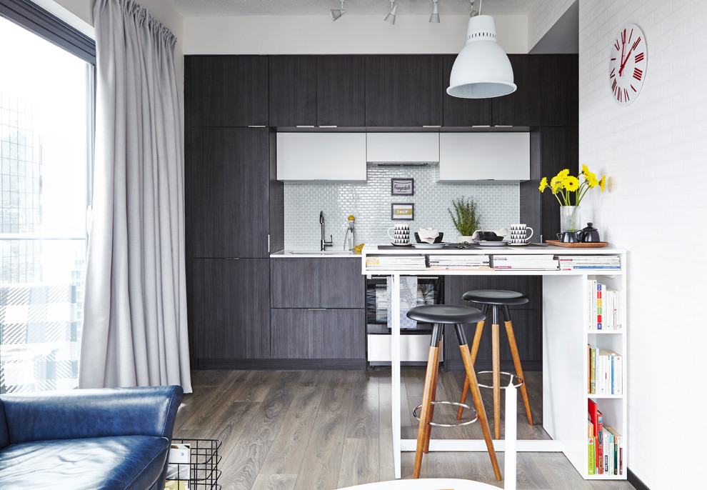 Offene Moderne Küche mit flächenbündigen Schrankfronten, dunklen Holzschränken, Küchenrückwand in Weiß, Küchengeräten aus Edelstahl, hellem Holzboden und Halbinsel in Toronto