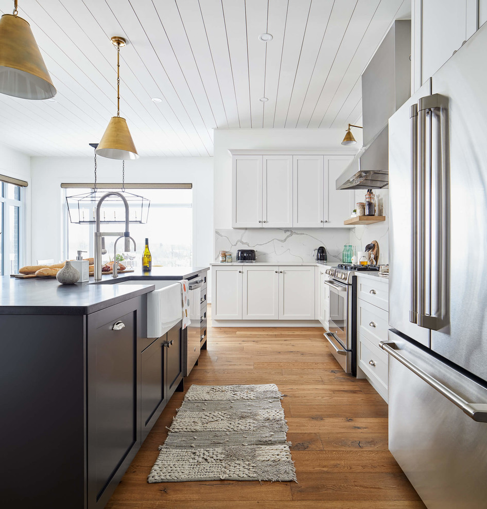 This is an example of a large traditional l-shaped kitchen/diner in Ottawa with a submerged sink, shaker cabinets, white cabinets, engineered stone countertops, white splashback, stainless steel appliances, light hardwood flooring, an island and white worktops.