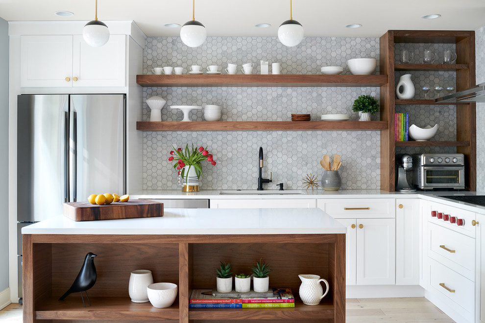 Example of a mid-sized transitional l-shaped light wood floor and beige floor kitchen design in Philadelphia with an undermount sink, shaker cabinets, white cabinets, solid surface countertops, gray backsplash, stainless steel appliances, an island and white countertops