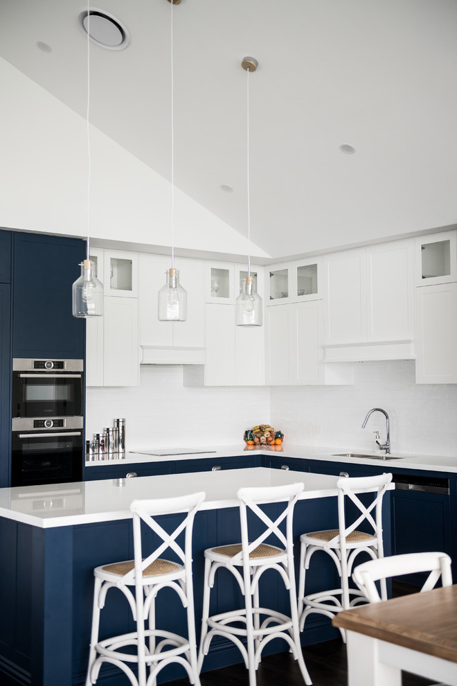 Esempio di un grande cucina con isola centrale costiero con lavello sottopiano, ante in stile shaker, ante blu, top in quarzo composito, paraspruzzi bianco, elettrodomestici in acciaio inossidabile e top bianco