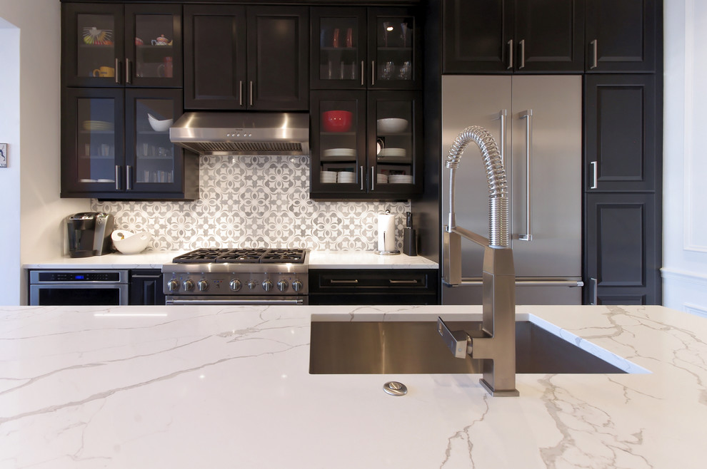 Inspiration for a mid-sized transitional galley ceramic tile and gray floor enclosed kitchen remodel in Baltimore with an undermount sink, raised-panel cabinets, black cabinets, quartz countertops, gray backsplash, marble backsplash, stainless steel appliances and an island