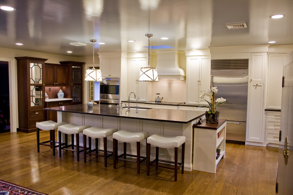 Example of a large classic single-wall open concept kitchen design in Philadelphia with an undermount sink, shaker cabinets, white cabinets, granite countertops, beige backsplash, ceramic backsplash, stainless steel appliances and an island