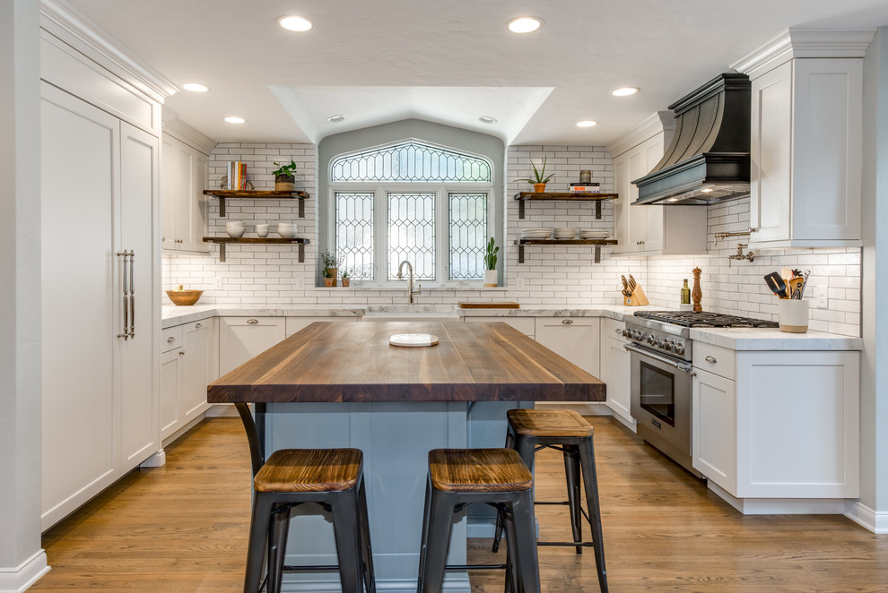 Bild på ett avskilt, mellanstort eklektiskt vit vitt u-kök, med en rustik diskho, släta luckor, vita skåp, bänkskiva i kvartsit, vitt stänkskydd, stänkskydd i tegel, integrerade vitvaror, mellanmörkt trägolv, en köksö och brunt golv