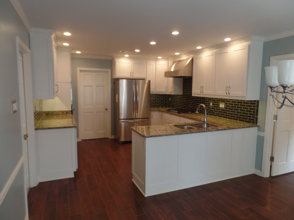 Large traditional u-shaped kitchen/diner in Nashville with a submerged sink, shaker cabinets, white cabinets, engineered stone countertops, green splashback, glass tiled splashback, stainless steel appliances, porcelain flooring and a breakfast bar.