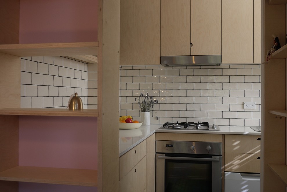 Cette image montre une petite cuisine design en bois clair avec un plan de travail en quartz modifié, une crédence en céramique et un sol en carrelage de céramique.