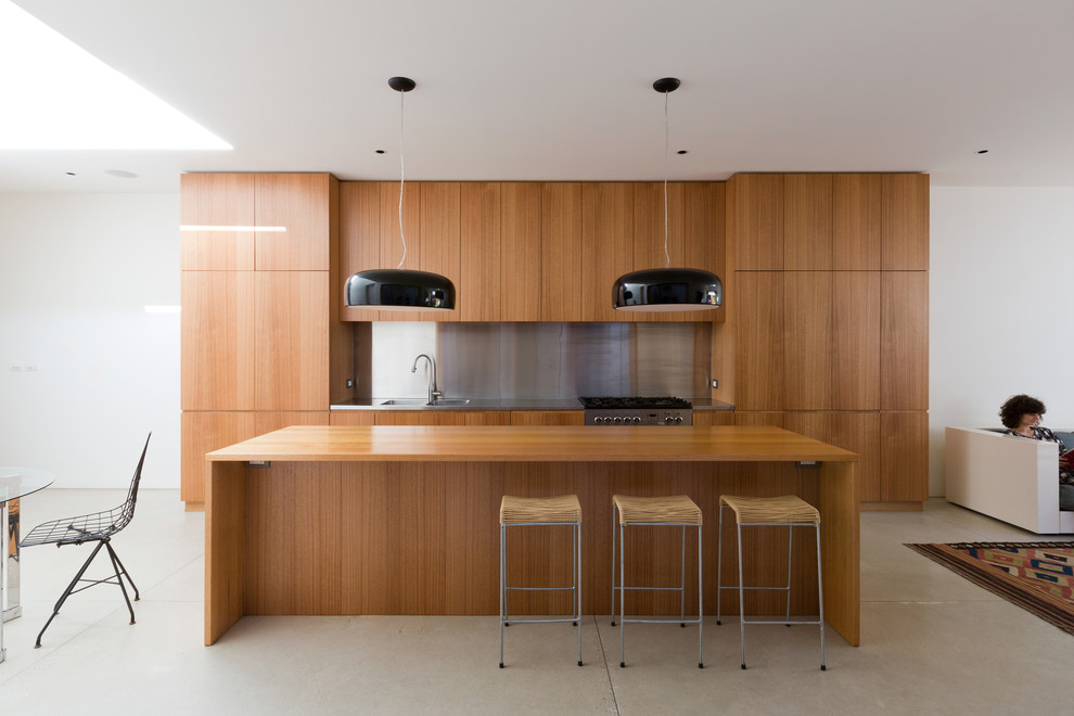 Exemple d'une cuisine ouverte linéaire moderne en bois brun de taille moyenne avec un plan de travail en bois, une crédence métallisée, un placard à porte plane, sol en béton ciré, un électroménager en acier inoxydable et îlot.