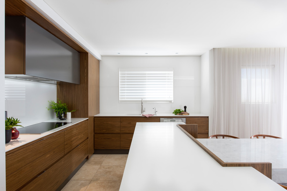 Photo of a medium sized modern l-shaped open plan kitchen in Sydney with a double-bowl sink, flat-panel cabinets, medium wood cabinets, composite countertops, white splashback, glass sheet splashback, stainless steel appliances, limestone flooring, an island and beige floors.