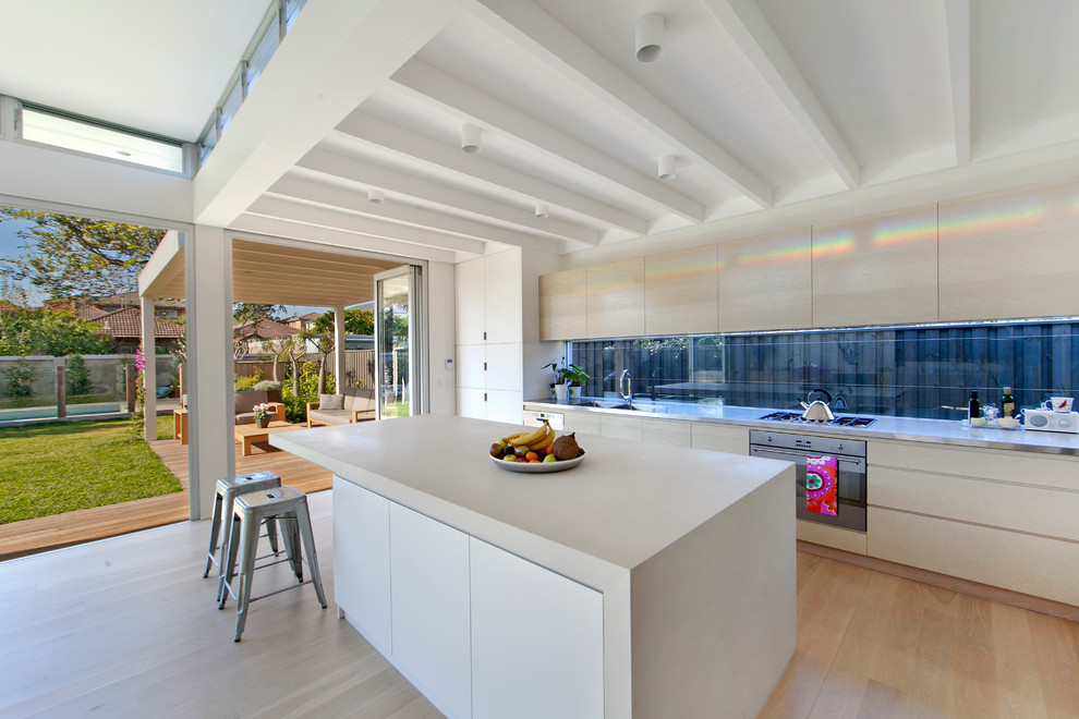 Zweizeilige Moderne Küche mit flächenbündigen Schrankfronten, hellen Holzschränken, Küchengeräten aus Edelstahl, hellem Holzboden und Kücheninsel in Sydney