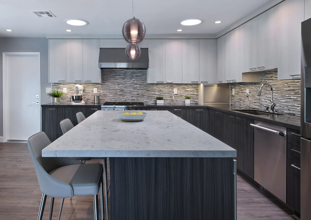 Inspiration for a mid-sized contemporary l-shaped gray floor and laminate floor eat-in kitchen remodel in Orange County with flat-panel cabinets, gray cabinets, porcelain backsplash, stainless steel appliances, an island, a drop-in sink, quartz countertops and multicolored backsplash