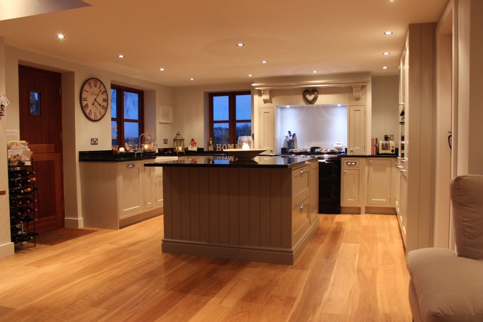 Inredning av ett klassiskt kök och matrum, med luckor med upphöjd panel, vita skåp, marmorbänkskiva, vitt stänkskydd och en köksö
