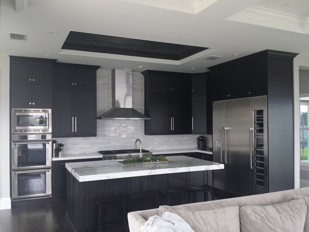 Design ideas for a medium sized classic l-shaped open plan kitchen in Miami with a submerged sink, shaker cabinets, black cabinets, marble worktops, white splashback, matchstick tiled splashback, stainless steel appliances, dark hardwood flooring and an island.