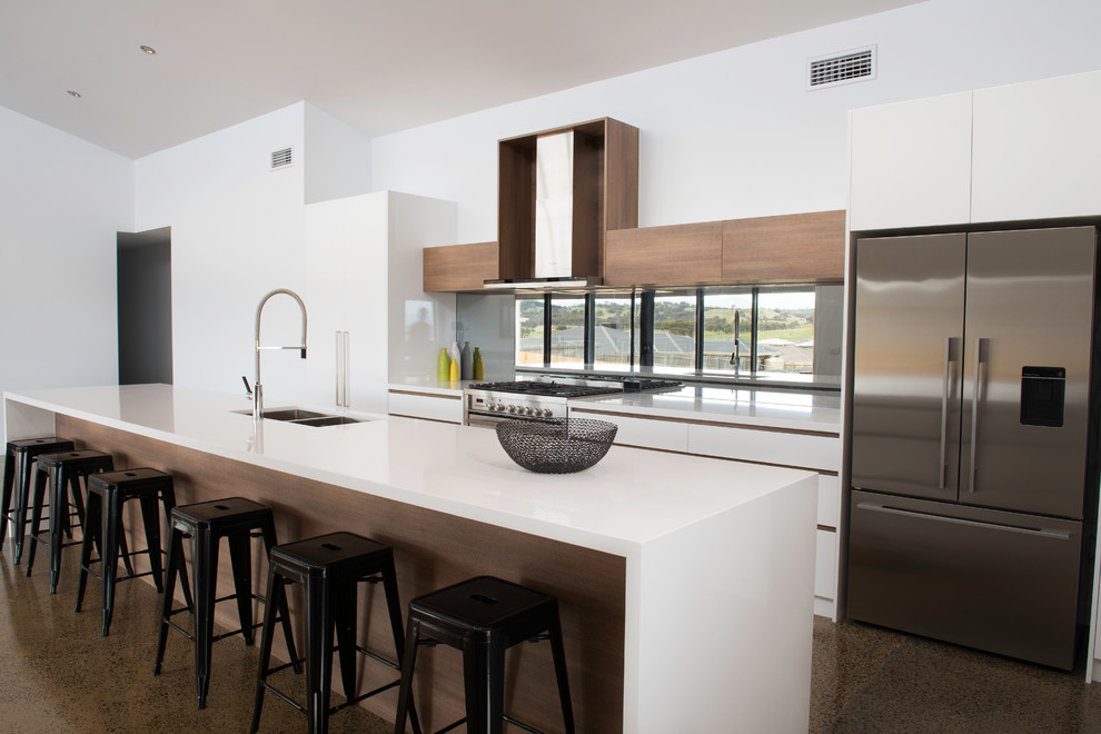 This is an example of a large modern galley kitchen/diner in Canberra - Queanbeyan with a submerged sink, flat-panel cabinets, white cabinets, granite worktops, grey splashback, mirror splashback, stainless steel appliances, concrete flooring and an island.