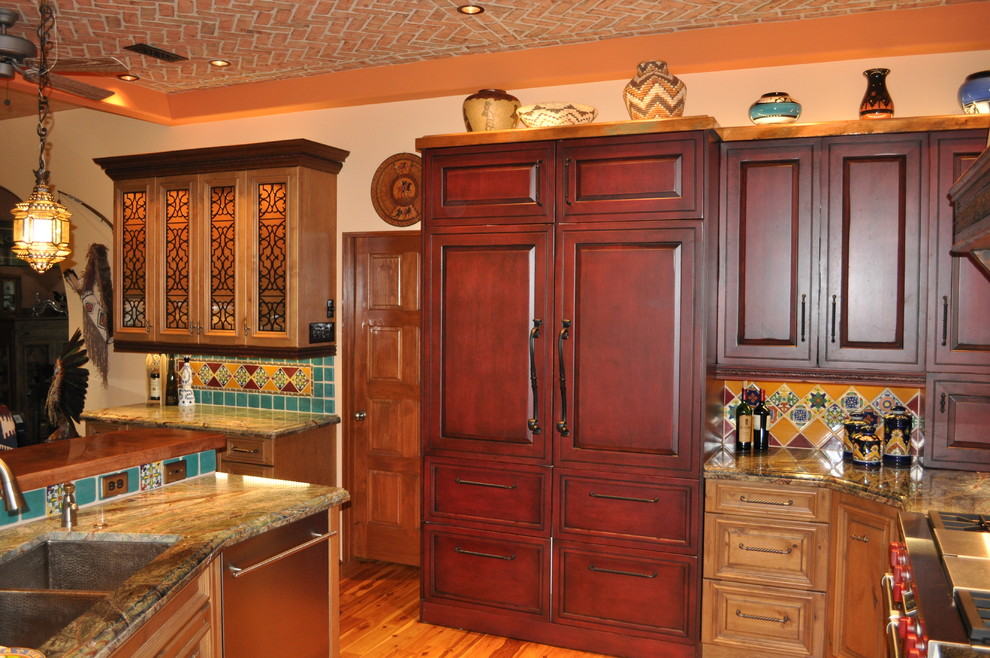 Exempel på ett stort medelhavsstil kök, med en dubbel diskho, luckor med upphöjd panel, skåp i mörkt trä, granitbänkskiva, flerfärgad stänkskydd, stänkskydd i keramik, rostfria vitvaror, ljust trägolv och en köksö
