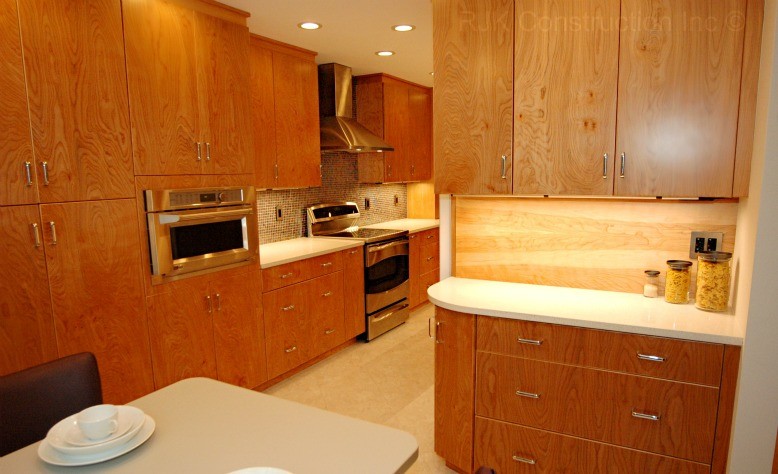 Foto på ett funkis kök, med en undermonterad diskho, släta luckor, skåp i mellenmörkt trä, flerfärgad stänkskydd, stänkskydd i mosaik och rostfria vitvaror