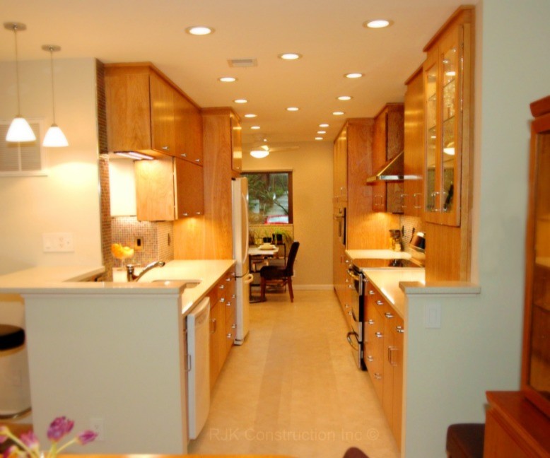 Photo of a contemporary galley kitchen/diner in DC Metro with a submerged sink, flat-panel cabinets, medium wood cabinets, multi-coloured splashback, mosaic tiled splashback, stainless steel appliances and no island.