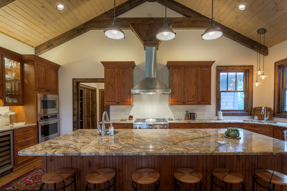This is an example of a large rustic u-shaped open plan kitchen in Charlotte with a submerged sink, raised-panel cabinets, medium wood cabinets, granite worktops, stainless steel appliances, medium hardwood flooring and an island.